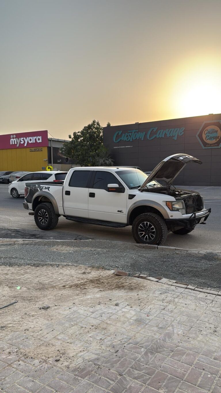 Technician providing roadside assistance in Dubai with emergency toolkit beside car
