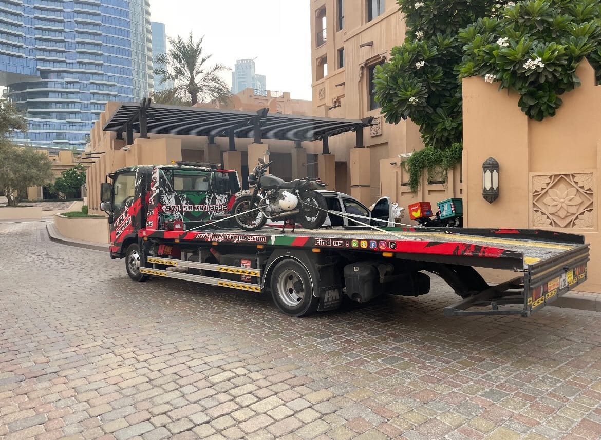 Motorcycle towing Dubai, TRT Recovery specialist loading a sport bike onto a flatbed truck